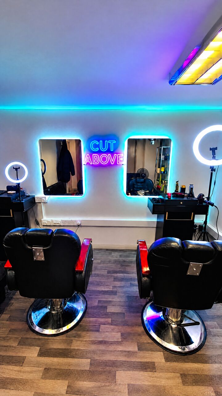 Backlit mirrors and the neon sign above both chairs