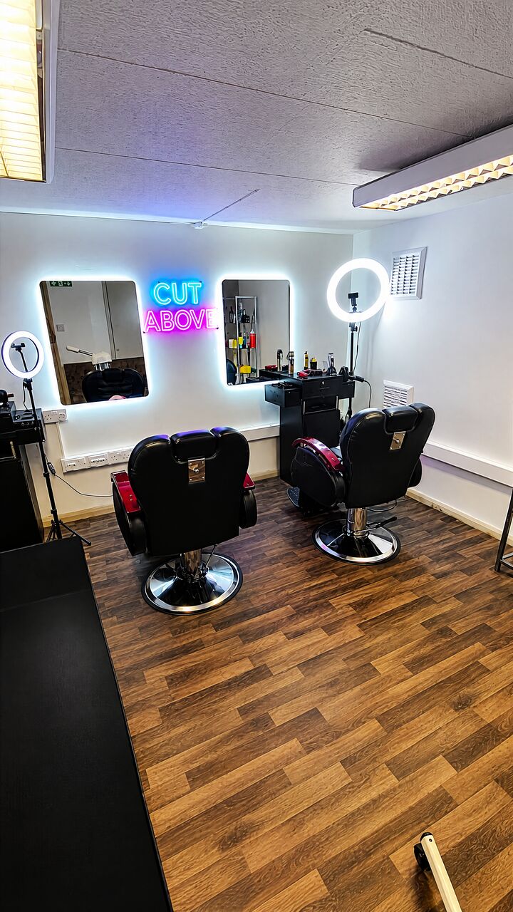 Both barber chairs under ring lights facing backlit mirrors